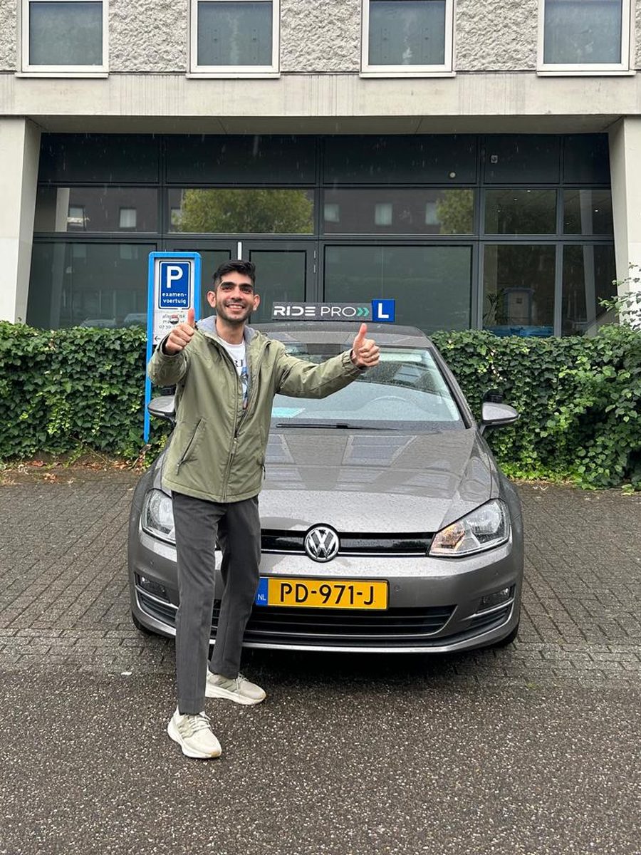Geslaagde RidePro-leerling met duimen omhoog naast de lesauto