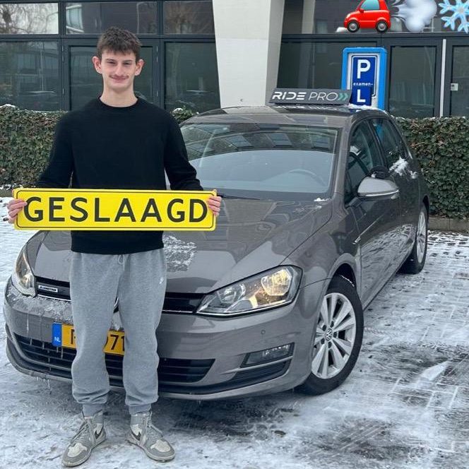 Jonge man staat naast een grijze auto en houdt een bord met "GESLAAGD" vast.